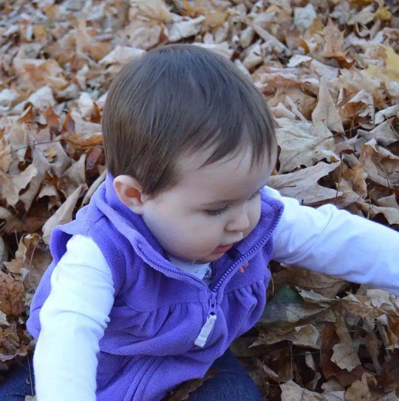 A young patient playing outdoors in autumn leaves